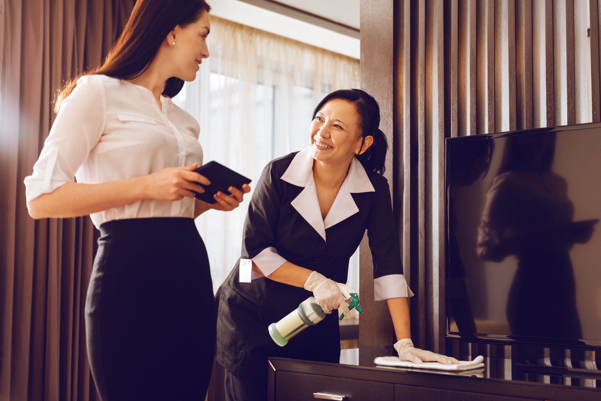 Positive delighted chambermaid polishing furniture